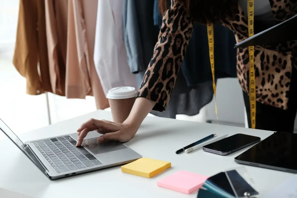 Imagem de uma dona de confecção mexendo em um notebook, cuidando do branding e marketing de moda da marca.