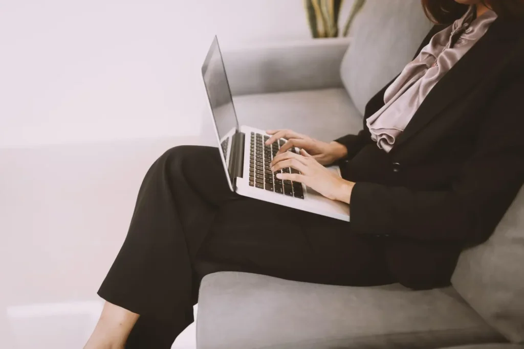 Estilista com notebook no colo, acompanhando um blog de moda.