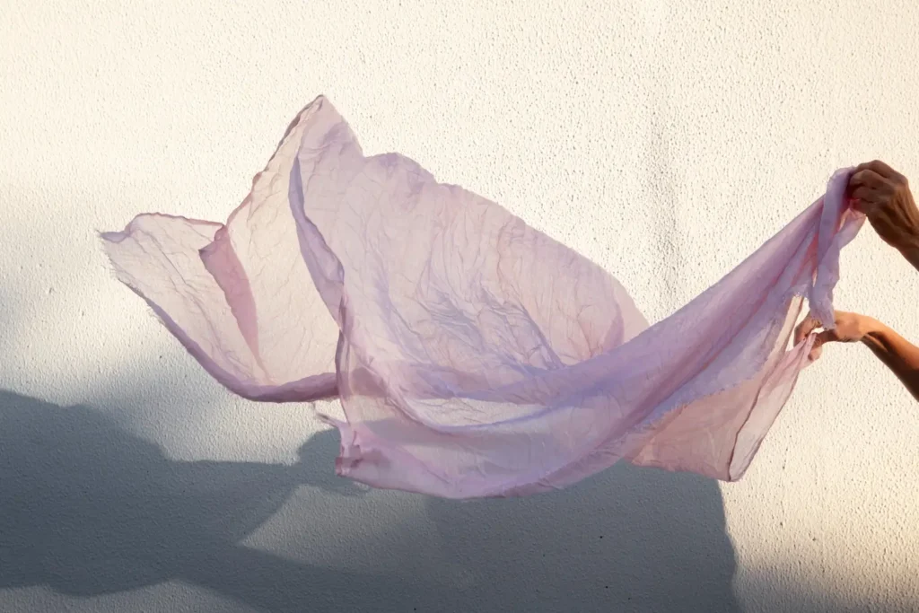 Uma mão segurando um tecido transparente rosa