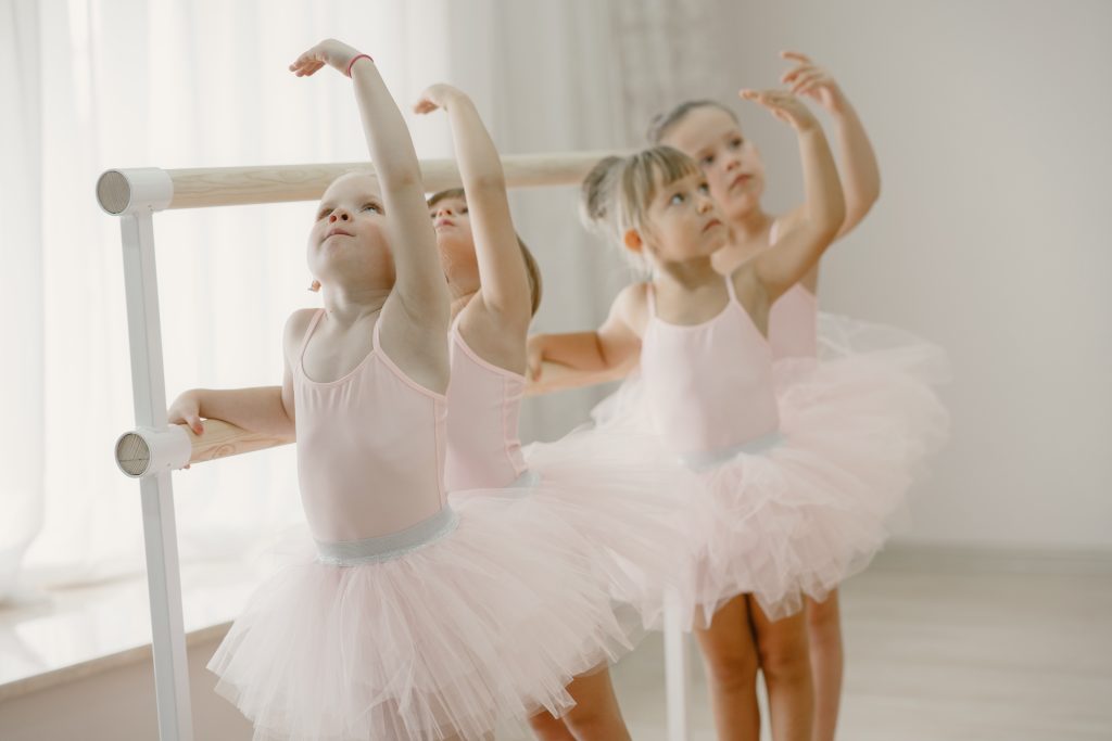 The image shows a group of little ballerinas wearing tutu skirts made of tulle fabric.