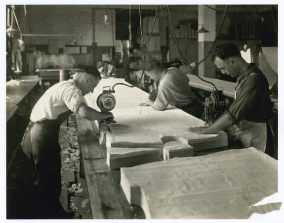Uomini che lavorano con tessuti tagliati in una fabbrica tessile durante la Seconda Rivoluzione Industriale
