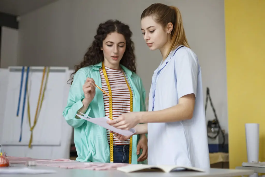 Fashion drawing: Two female designers evaluating a technical drawing. 