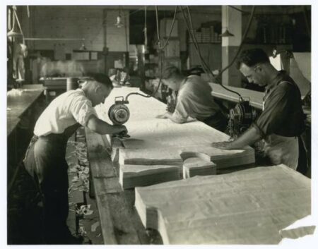 Men working with cut fabrics in a textile factory from the Second Industrial Revolution period.
