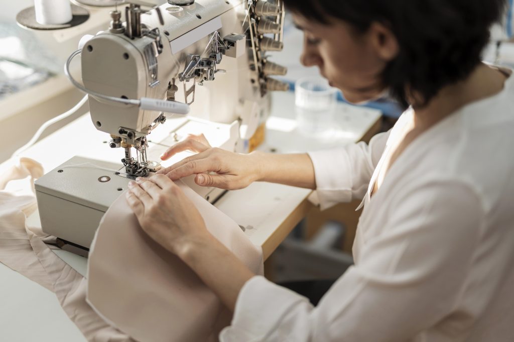 The image shows a fashion professional operating a sewing machine in the context of Industry 5.0.