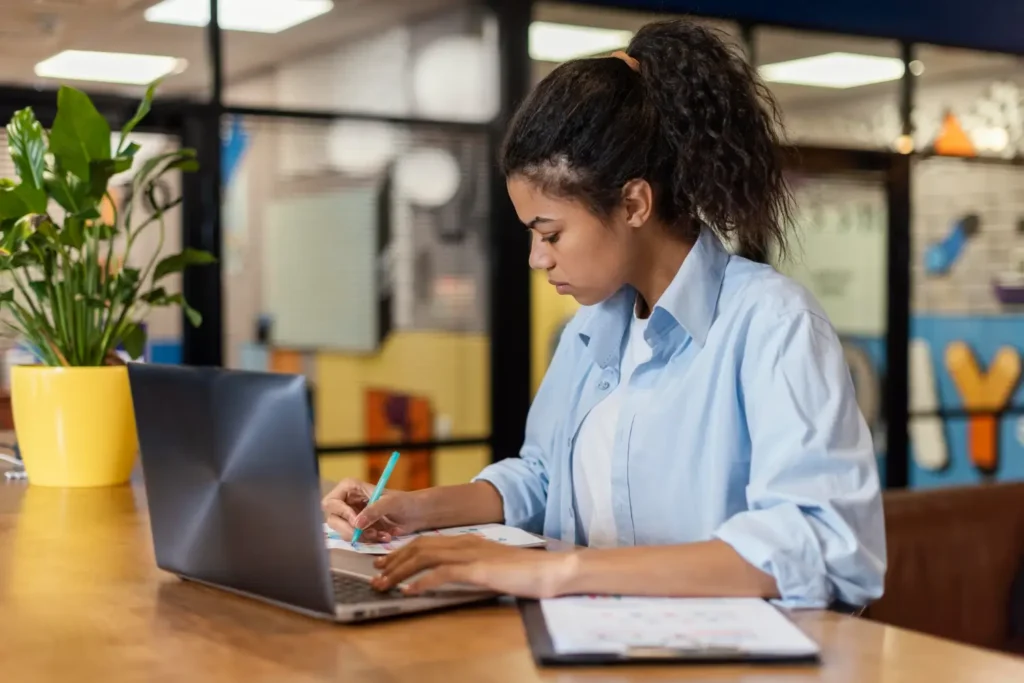Mulher usando SaaS no trabalho e fazendo anota&ccedil;&otilde;es