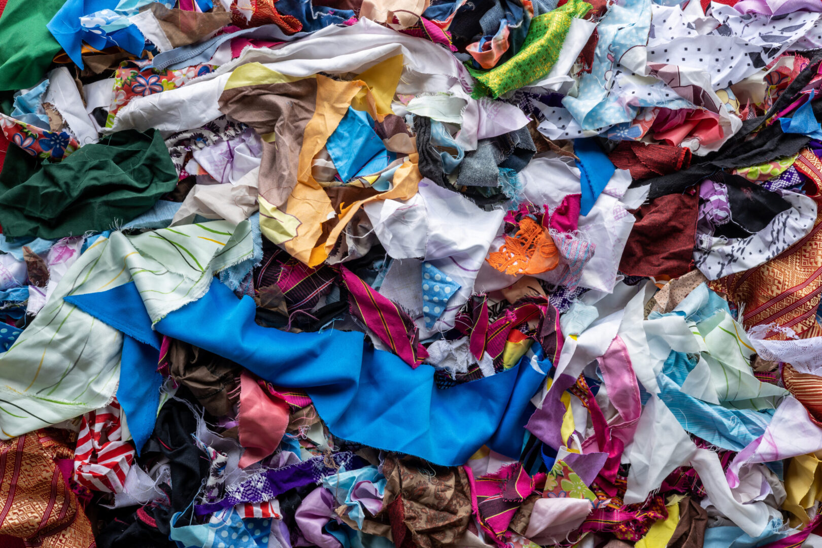 Image shows a pile of textile waste, with rag pieces of different colors