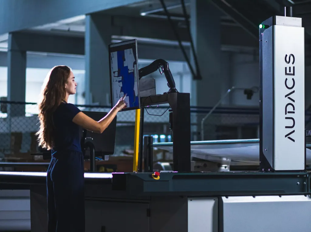 Woman operating an Audaces automated fabric cutting machine