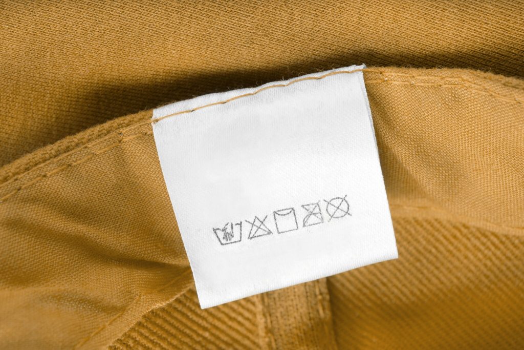 Care clothing label on yellow textile background.