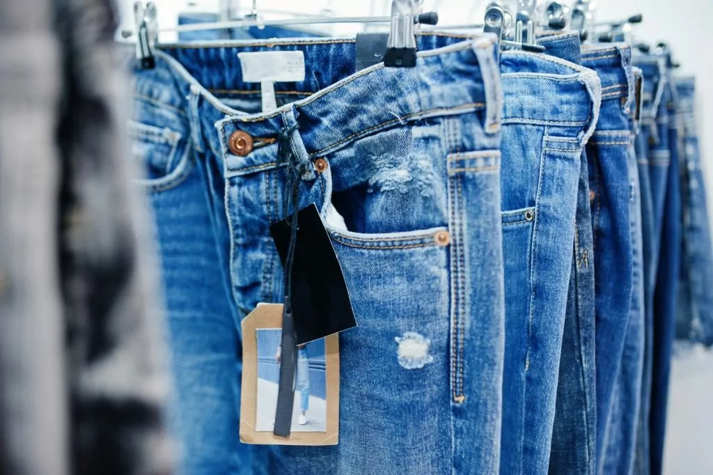 Perfect fit fabrics: Blue jeans pants hanging on a rack.