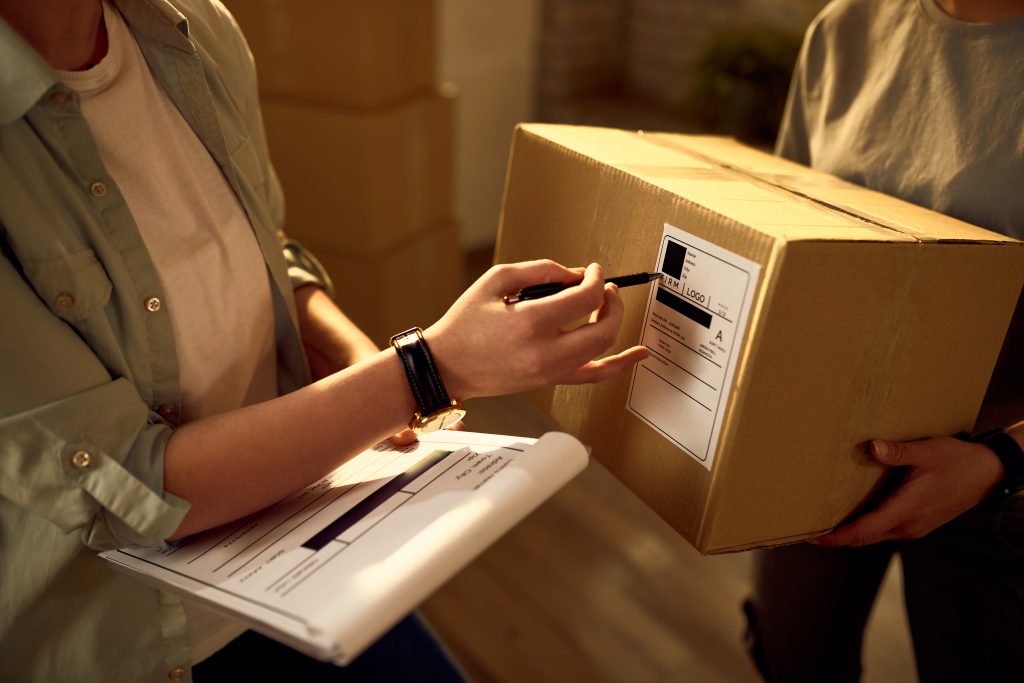 Woman checking information on an order box while conducting apparel inventory management at a company.