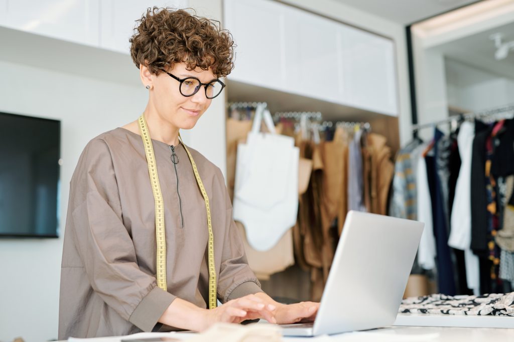 Fashion brands: Female professional of clothes design standing in front of laptop.