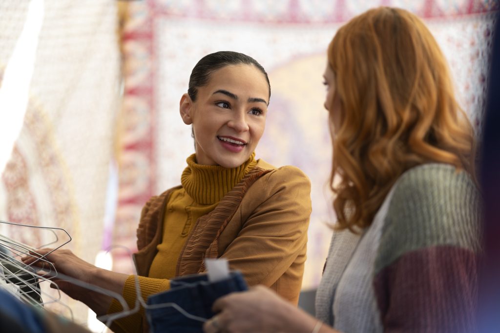 Two women chatting about the benefits of a well-structured fashion sales pitch while shopping in a store. 