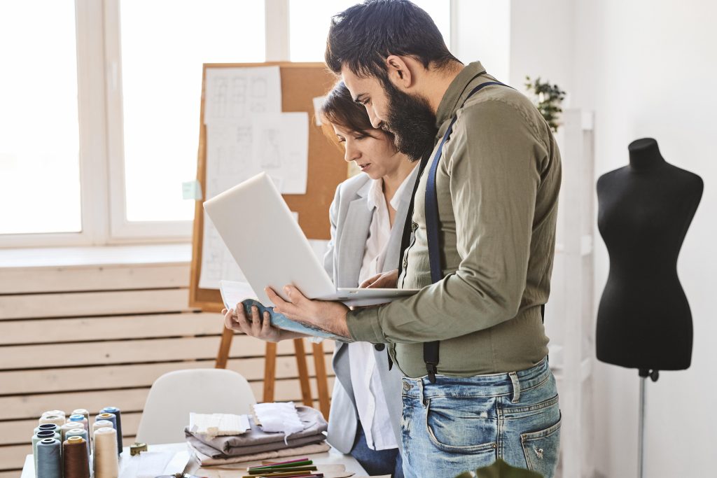 A man and woman in a menswear atelier discussing an outfit. 