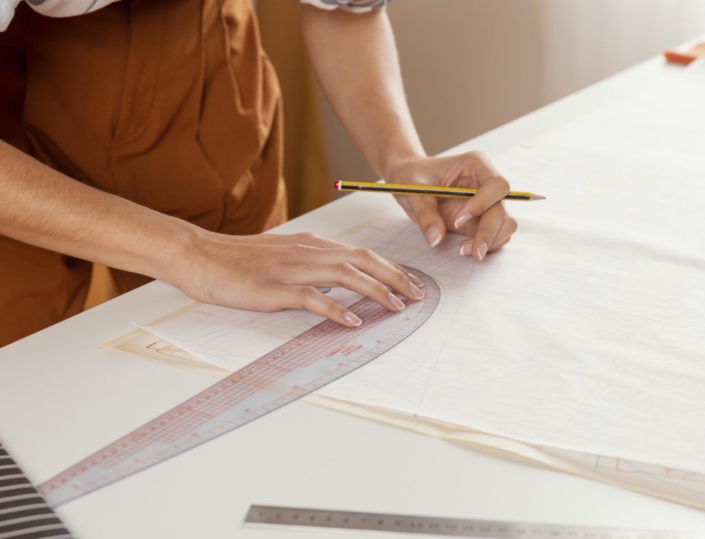 Modeling techniques: Woman drawing on fabric, using the flat pattern-making method. 