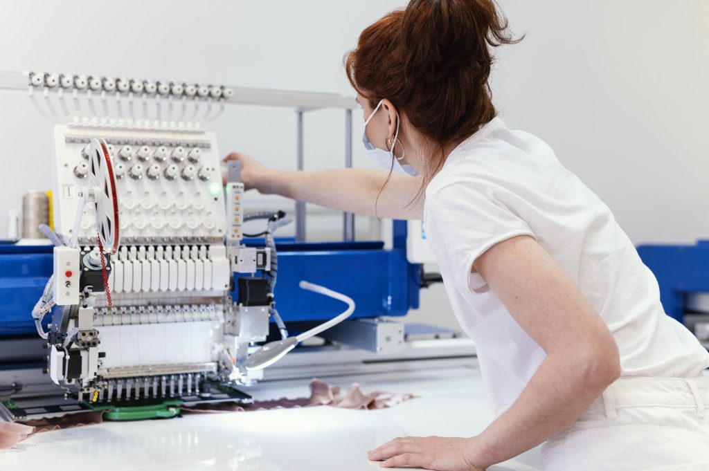 Mulher arrumando máquina para produção em empresas têxtil 