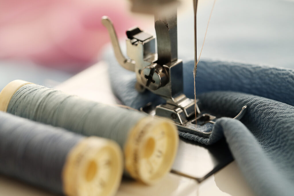 Máquina de costura em cima da mesa com linhas em tecido 