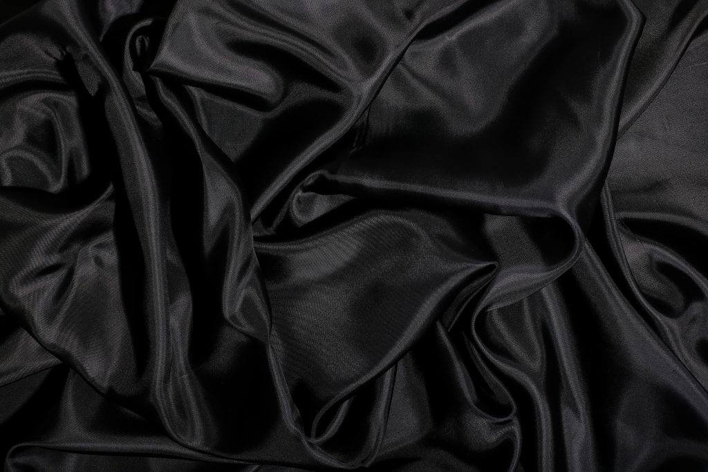 Fabric composition: A black glossy silk swatch. 