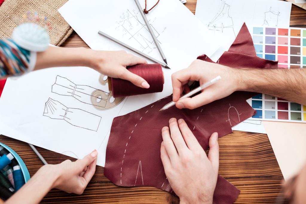 Fashion designers drawing sewing darts on a pattern.