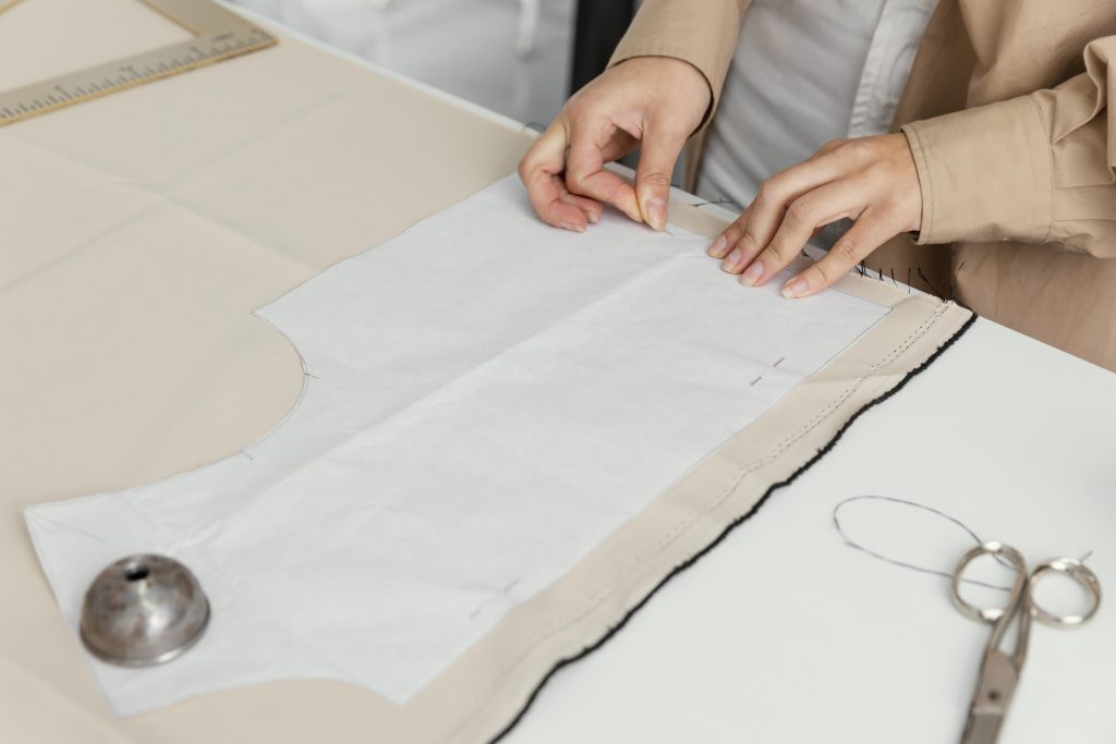 Fashion designer marking sewing darts on a clothing pattern.