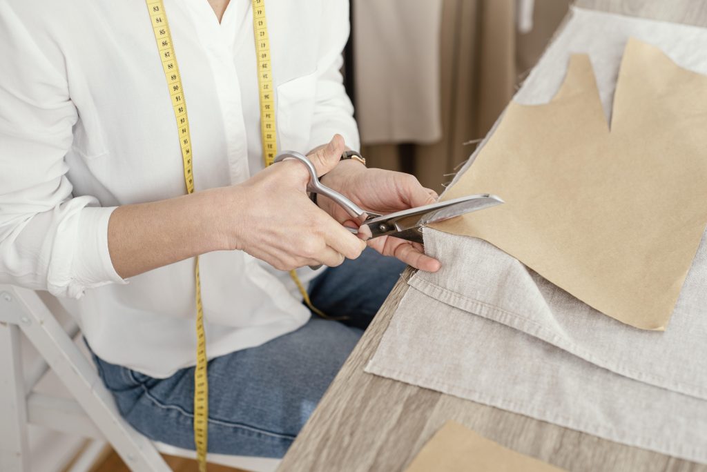 Diseñadora cortando tela para venta al por menor de ropa