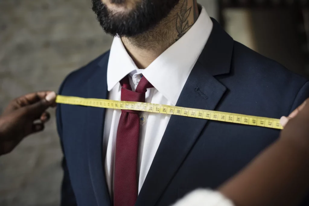 Tamanhos de roupas masculinas: homem tirando medidas do tórax de um cliente 