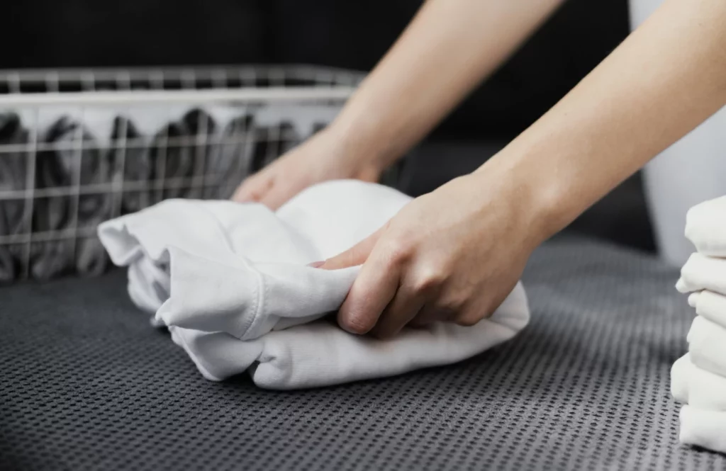 Homem dobrando roupas em um dos processos de lavanderia industrial 