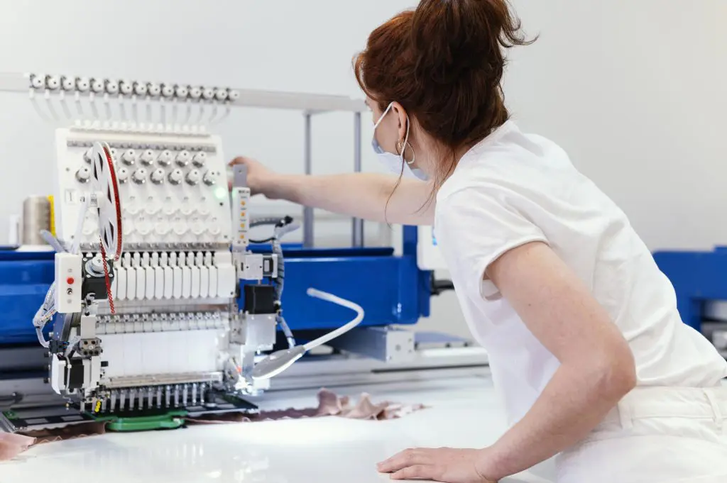 Woman adjusting a machine to start production in a textile business. 