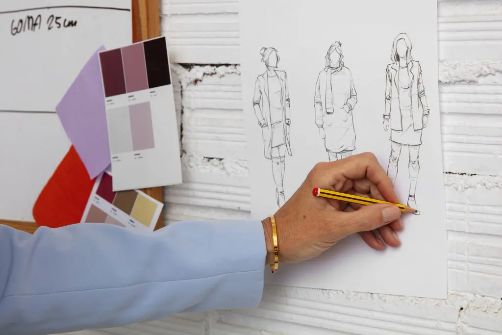 Woman drawing flat sketches that will be part of the textile flowchart of her fashion production. 