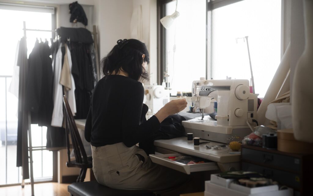 Mulher costurando peças de roupa em máquina de costura