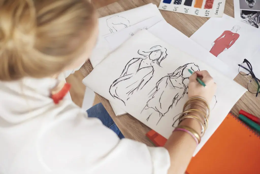 Woman drawing fashion sketches on paper