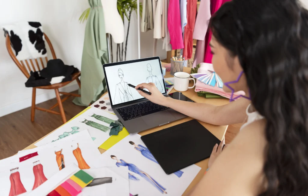 Mulher criando desenhos rápidos de roupas em computador 
