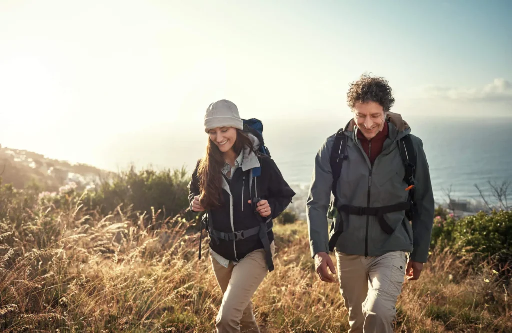A man and a woman hiking using appropriate garment types.