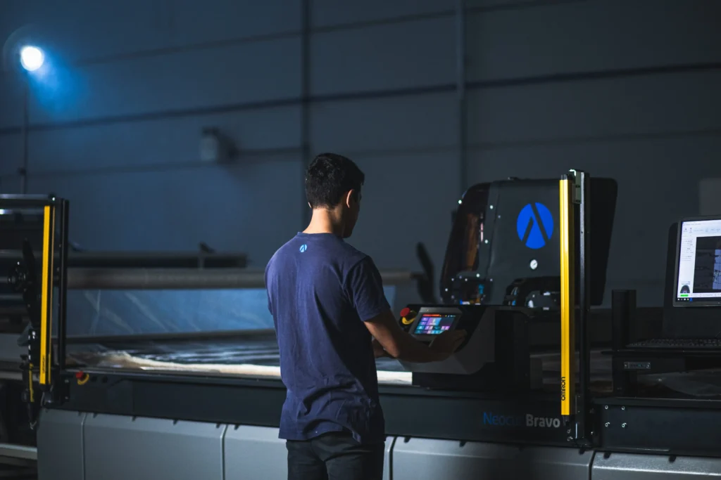 A textile worker operating an automatic cutting machine.