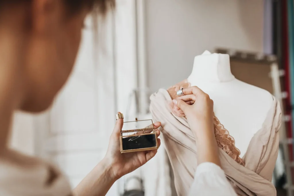 Mulher estilista alfinetando modelo de vestido em um manequim.