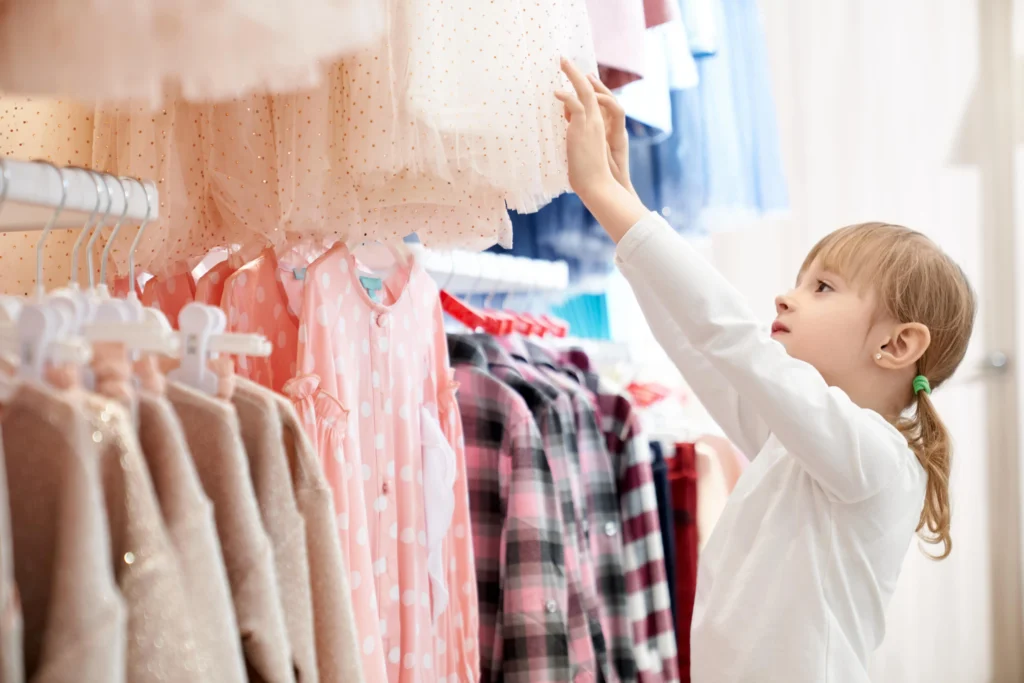 niña eligiendo una prenda en una fábrica de ropa para niños