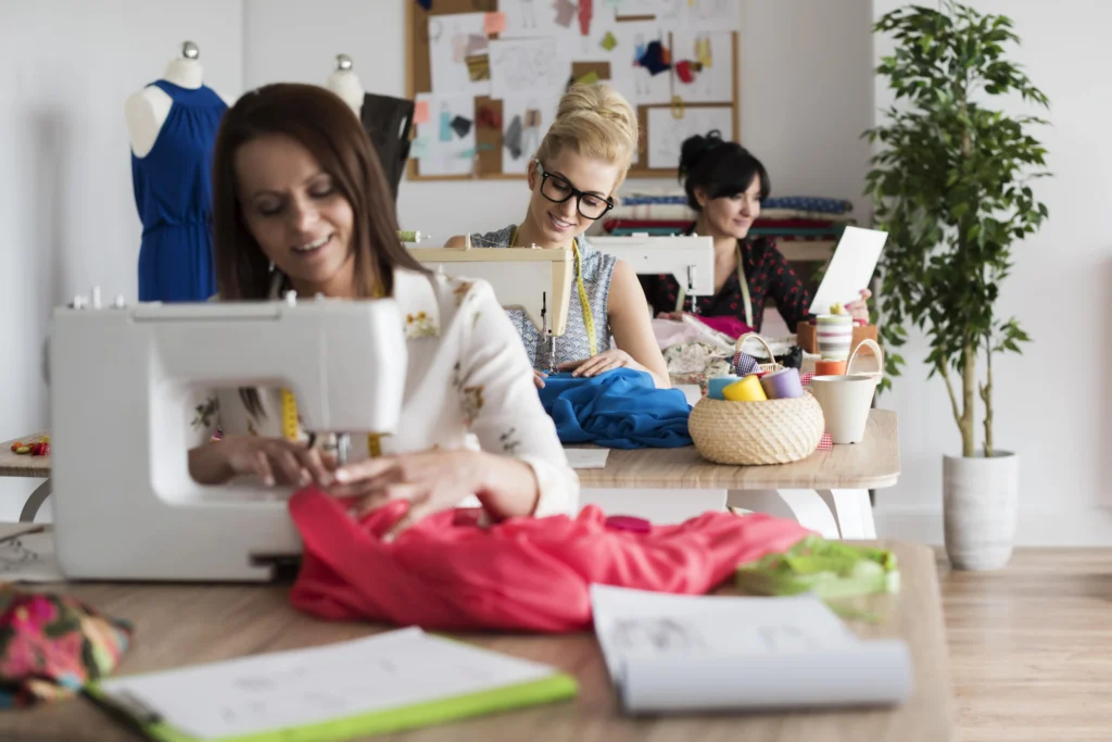 3 diseñadoras cosiendo ropa en un taller de costura