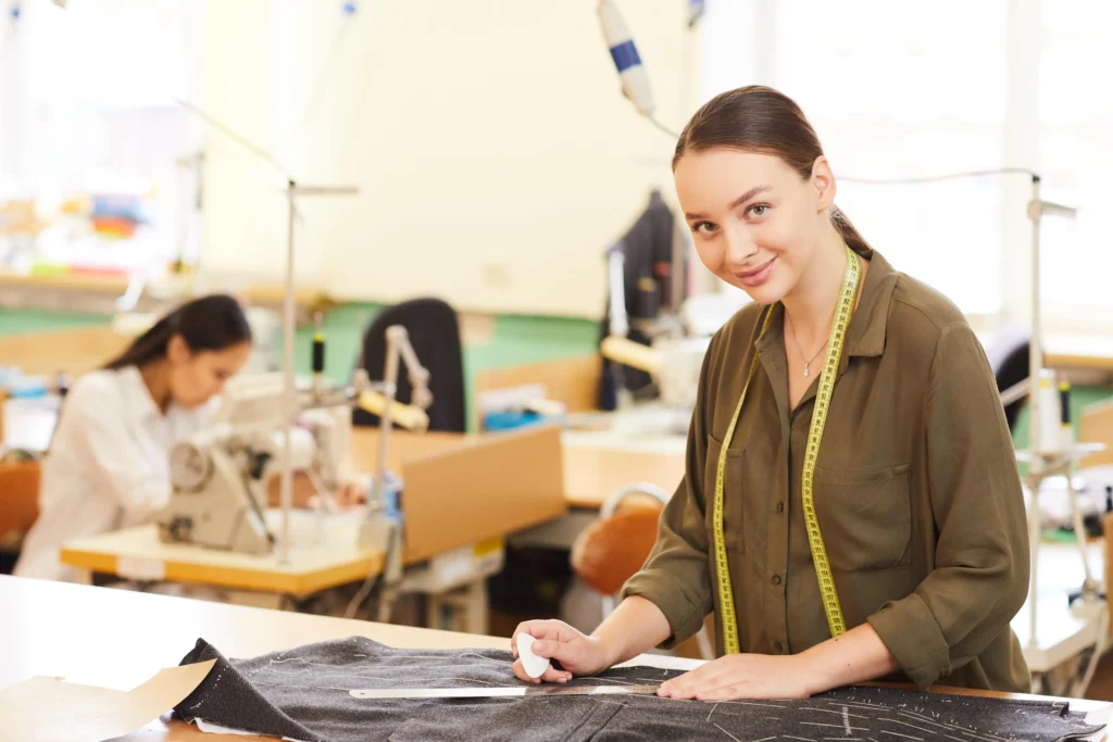 Mujer trabajando en una fábrica de ropa, utilizando tecnología de patronaje industrial para crear patrones de prendas con precisión.