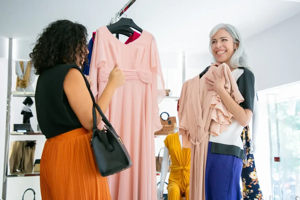 Vendedora e cliente olhando para diferentes tipos de vestido