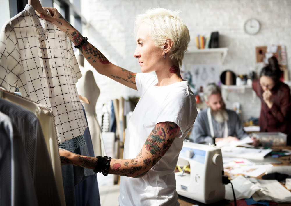 The image shows a fashion designer examining a grid-patterned shirt in a bright studio. It highlights the blend of creativity and efficiency essential for mass customization in fashion.