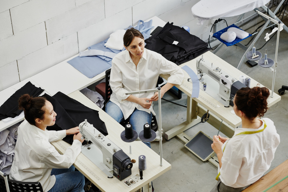 Three women discussing work in a clothing factory. Communication is key to improving production capacity.