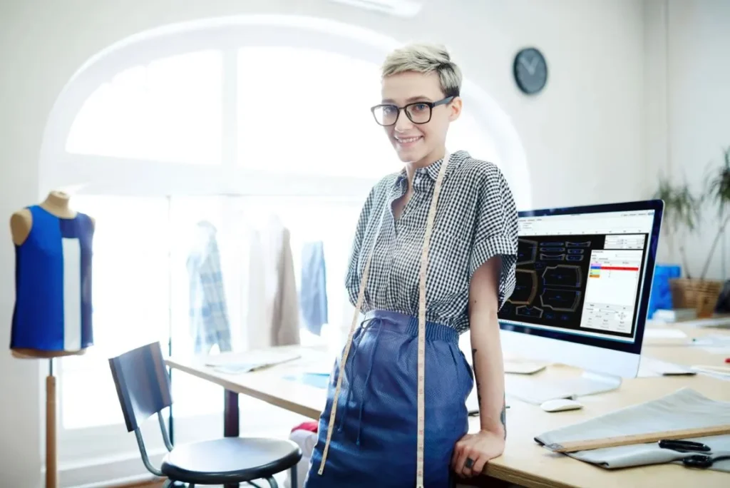 A pattern maker with a measuring tape around her neck, demonstrating how to take body measurements.