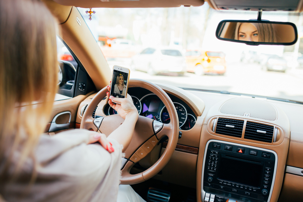 Emerging auto trends: A young woman looking at her phone in a car.