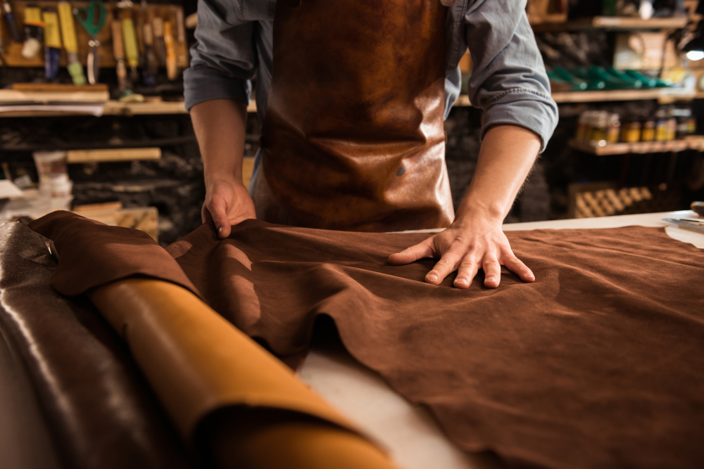 Leather cutting tools: a professional handling the material before cutting.