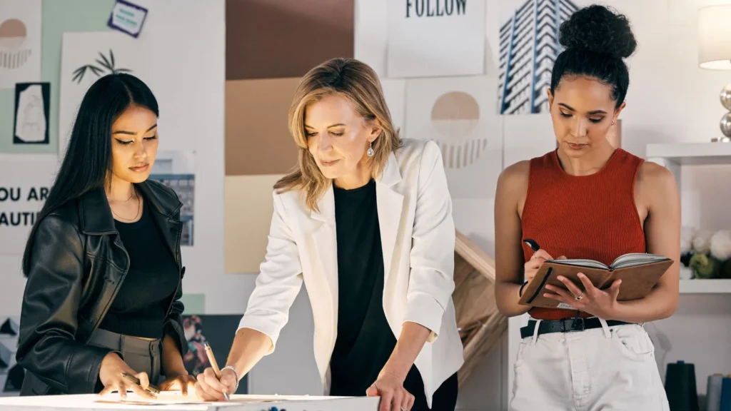 En un estudio de diseño, un grupo de estilistas revisa sus bocetos mientras en pantalla se proyectan looks inspirados en microtendencias.