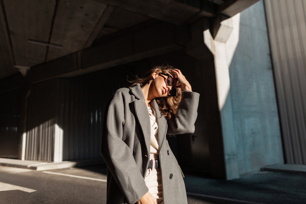 Types of coats: a woman wearing sunglasses and a long gray coat.