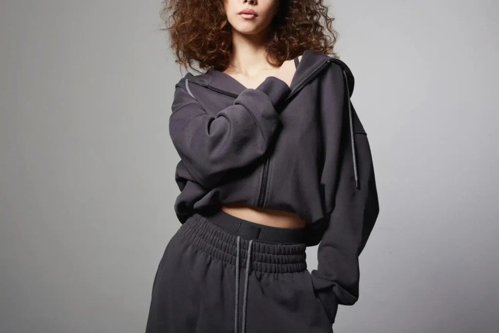 Modelo com um conjunto de moletom escuro, uma das peças de roupas mais versáteis que existe.