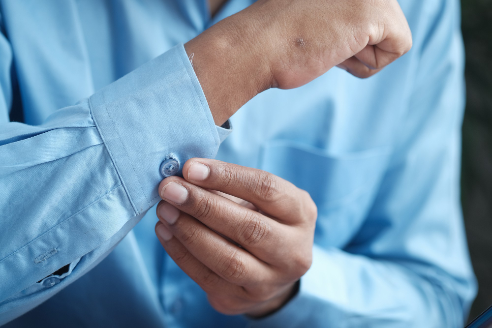 Types of cuffs: A man fixing the cuff of his light blue shirt.
