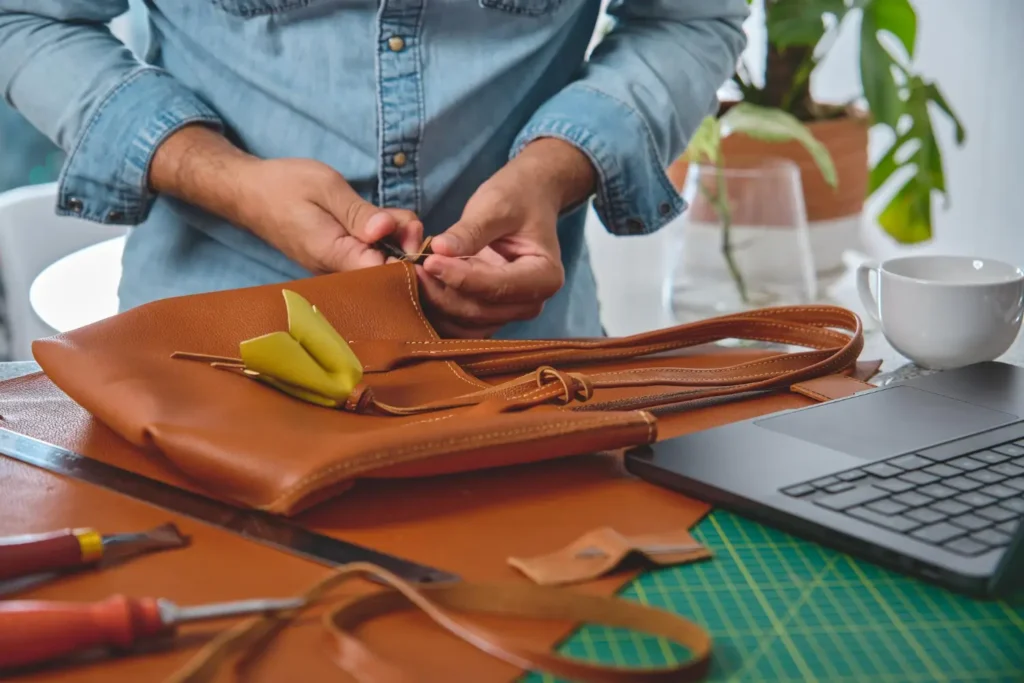 Designer de bolsas costurando e finalizando uma bolsa de couro