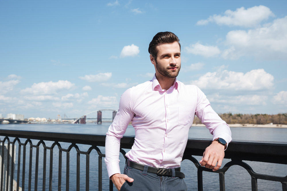 Types of shirts: A man in a light pink shirt standing in front of the sea.