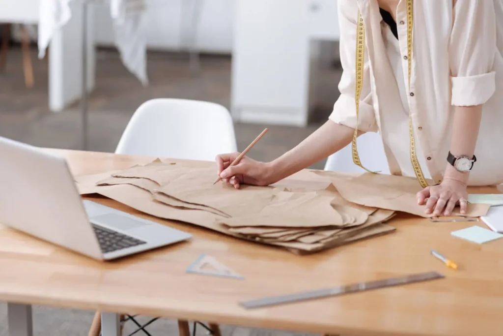 Patronista midiendo con cinta métrica diferentes tipos de patrones en papel.